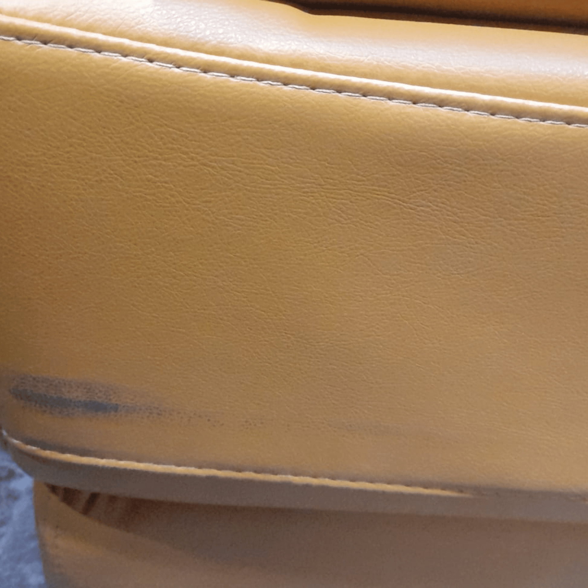 Close-up of a yellow leather surface with visible stitching