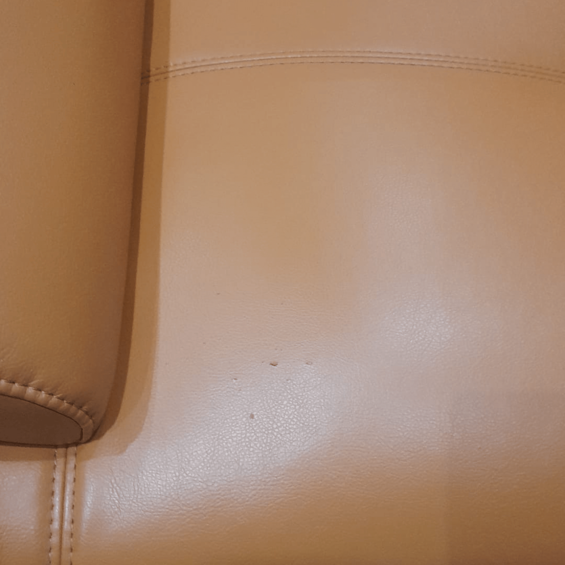 Close-up of a beige leather surface with a stain.