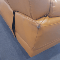 Brown leather sofa with a visible tear on a blue carpet