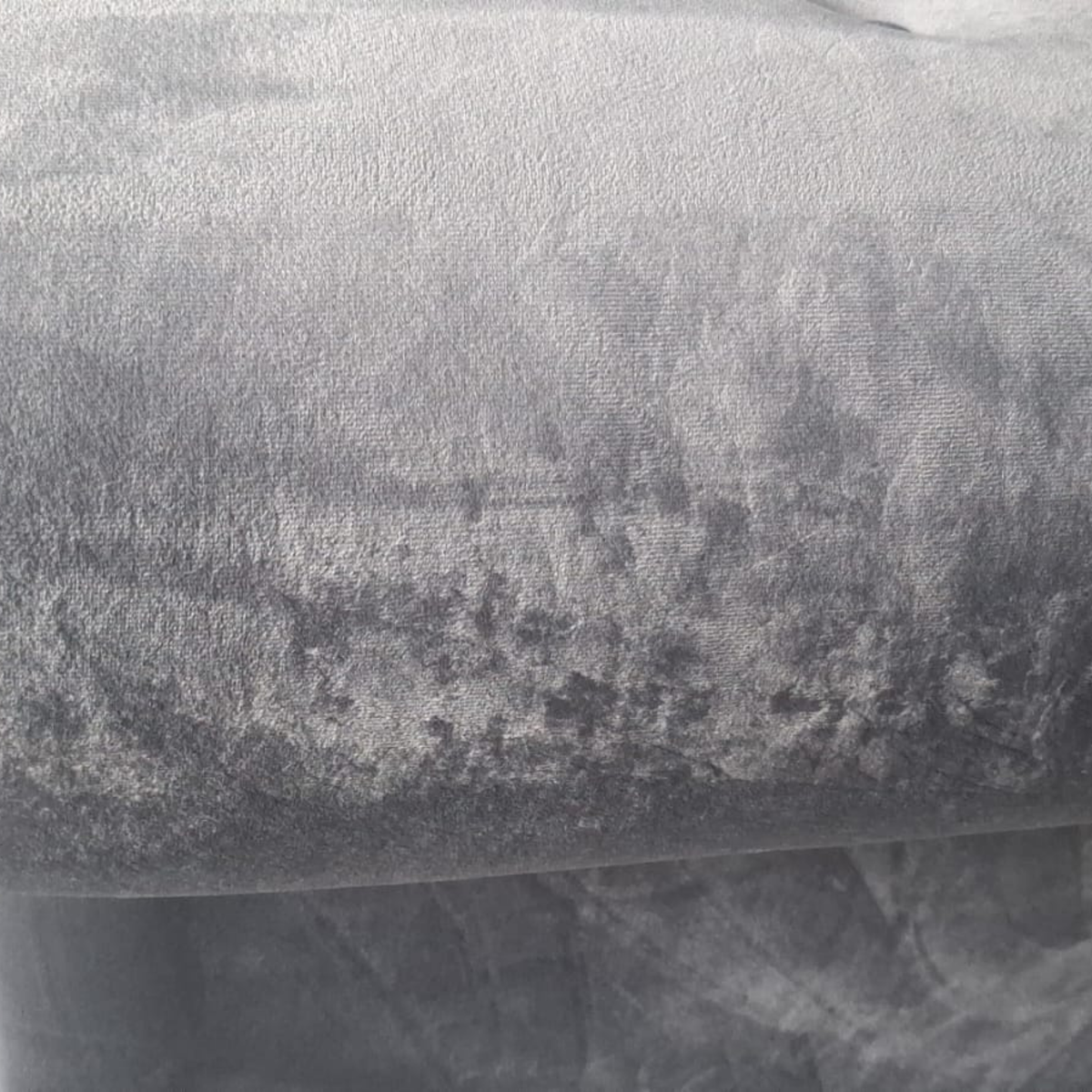 A close-up of a textured gray fabric, showing a mottled pattern with lighter and darker gray areas.