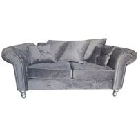 A gray velvet loveseat sofa with rolled arms, silver nailhead trim, and silver-toned legs, accompanied by four matching gray throw pillows, shown against a plain white background.