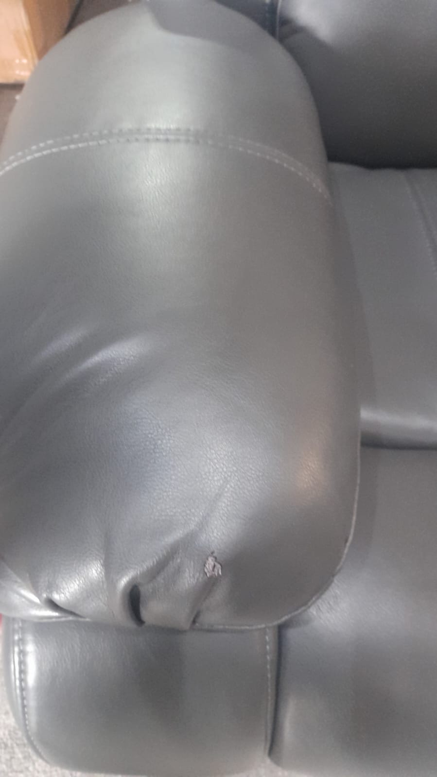 Close-up of the armrest on the Valerie grey leather 3-seater sofa, highlighting the smooth texture and stitching detail