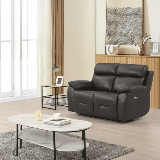Modern living room with a black leather sofa, coffee table, and decorative items.