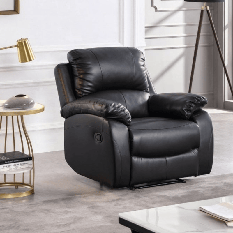 Black leather recliner chair in a living room setting with a side table and lamp.