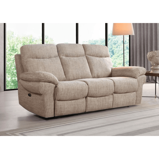 Beige reclining sofa in a living room setting with large windows and a lamp.
