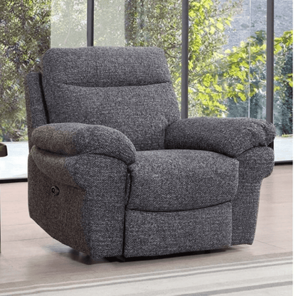 Gray recliner chair in a room with large windows showing greenery