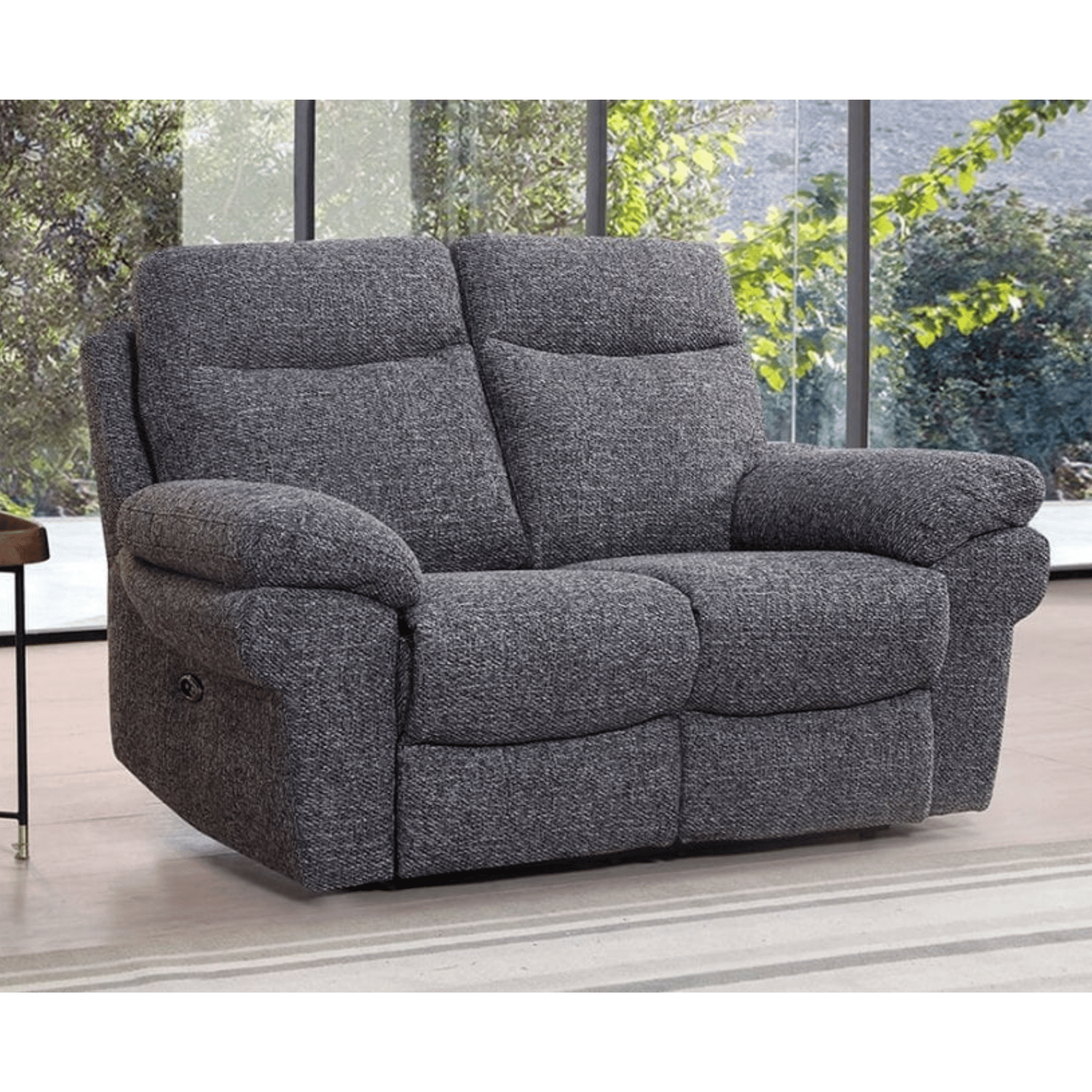 Gray recliner sofa in a room with large windows showing greenery outside.