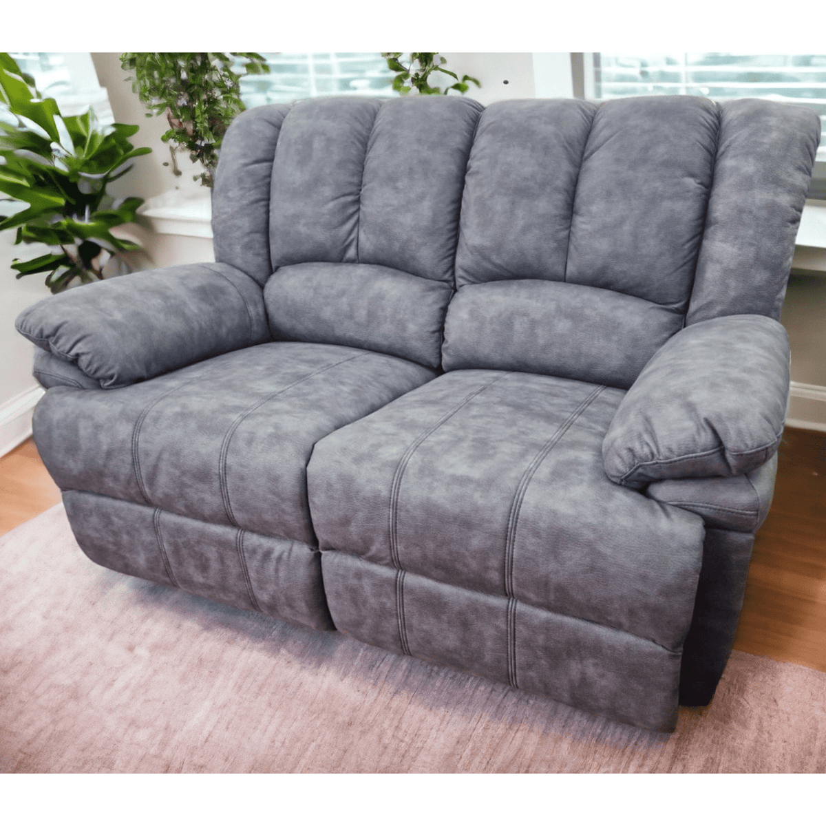 Gray sofa in a living room setting with plants and a window.