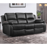 Black leather sofa in a living room setting with a rug and wall art.