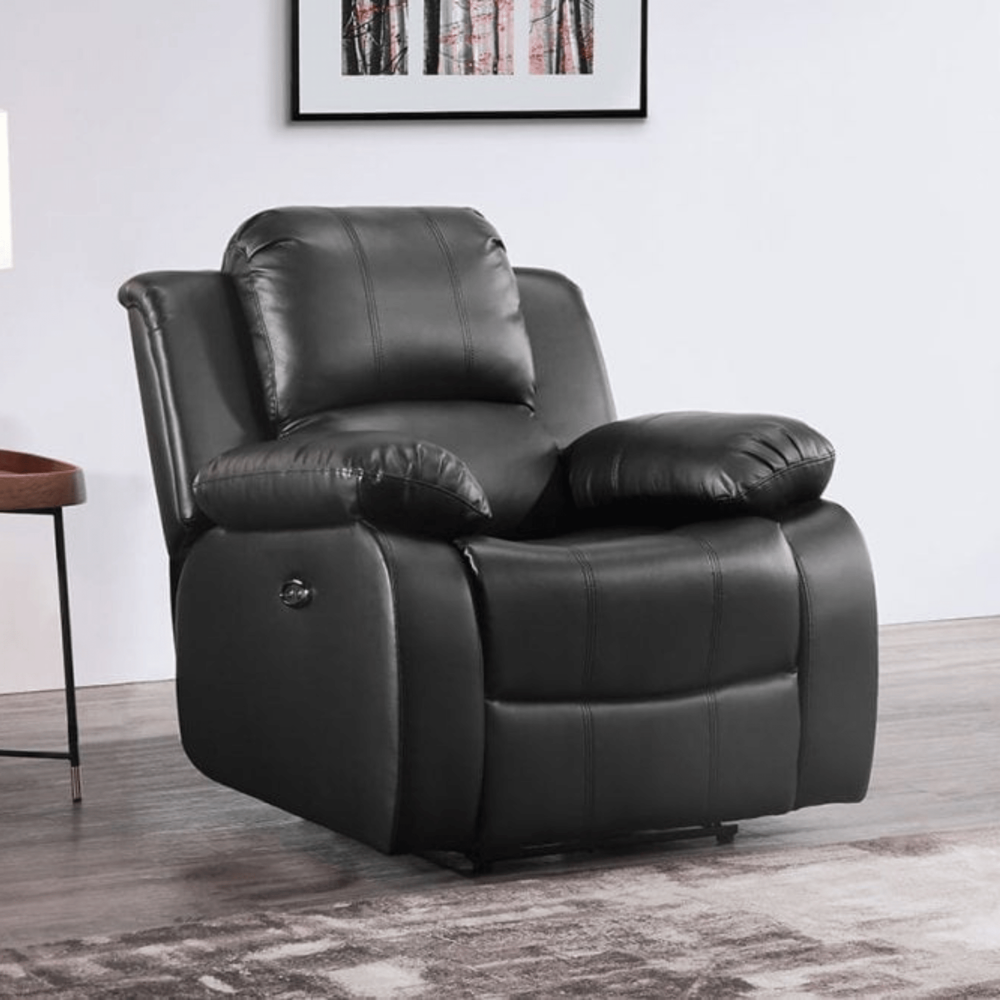 Black leather recliner chair in a room with a framed picture on the wall.