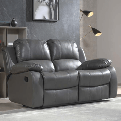 Gray leather reclining sofa in a living room setting with a lamp and wall art.