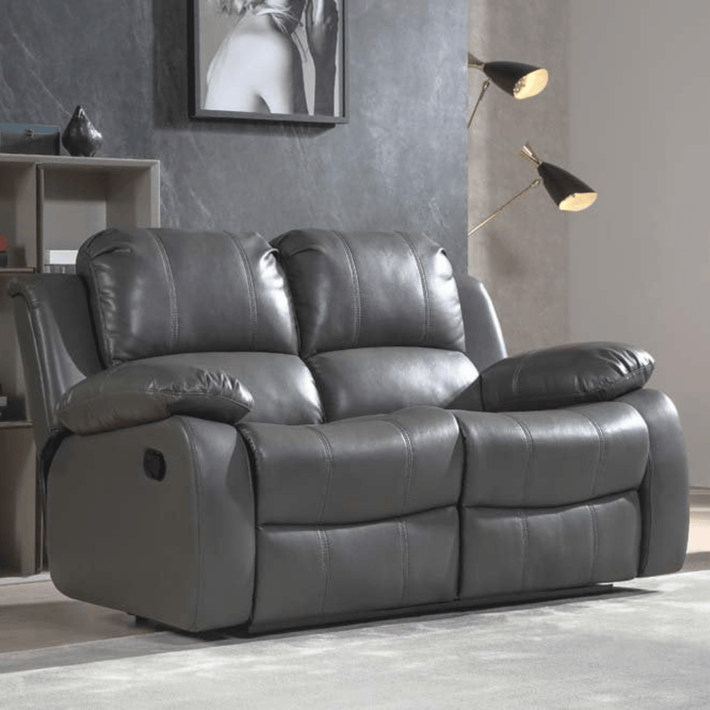 Gray leather reclining sofa in a living room setting with a lamp and wall art.