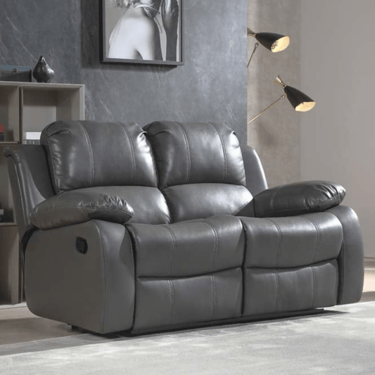 Gray leather reclining sofa in a living room setting with a lamp and framed picture on the wall.