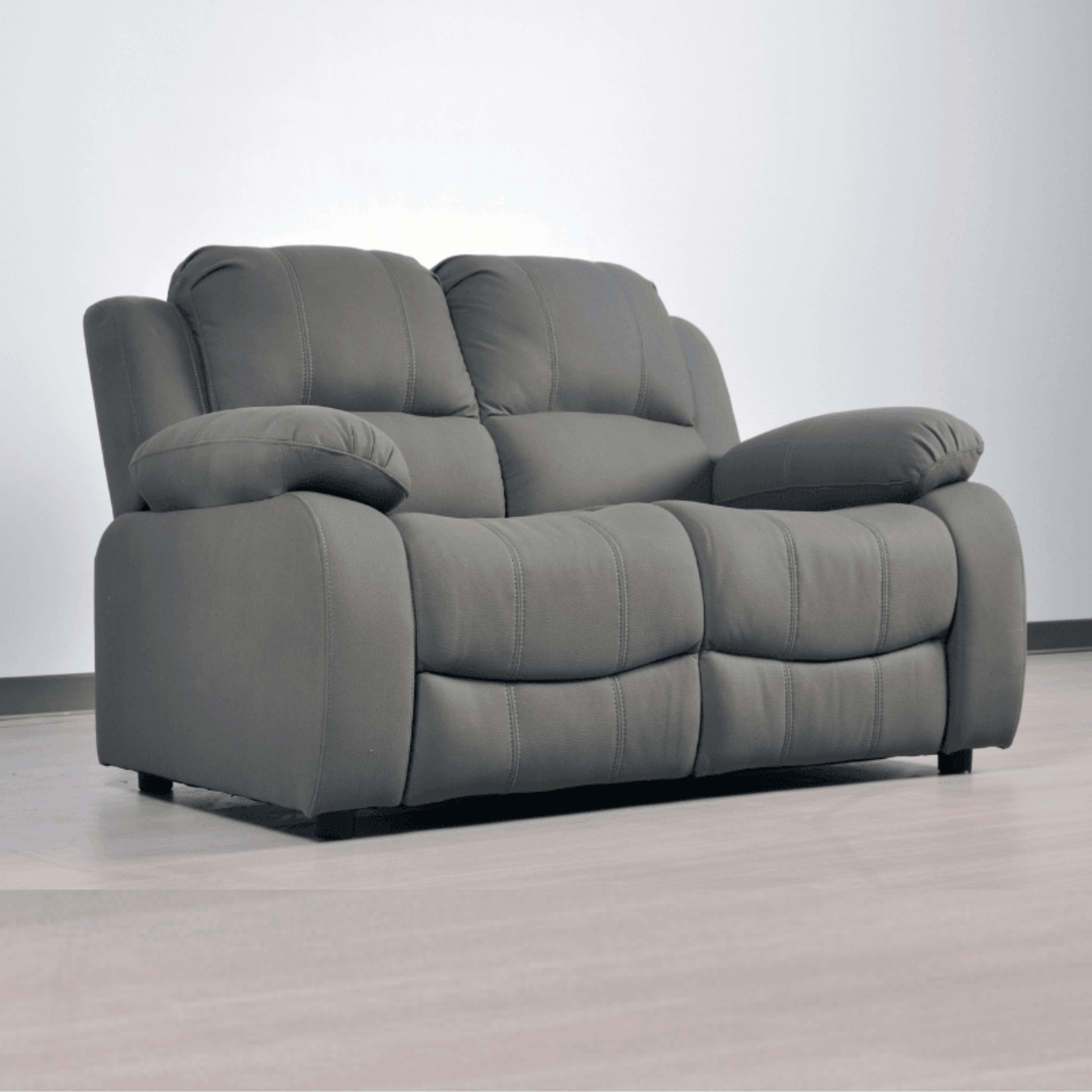 Gray recliner sofa on a light gray floor with a white wall background