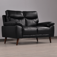 Vantage 2-seater black sofa in a modern living room set, angled view with decor and soft ambient lighting.