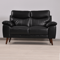 Vantage 2-seater black sofa in a modern living room set, front-facing view with decor and soft ambient lighting.