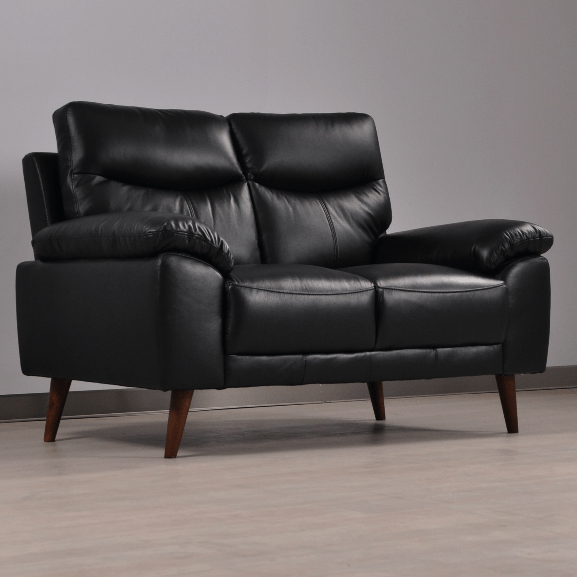 Vantage black 2-seater sofa at an angle in a contemporary living room with neutral tones and soft lighting