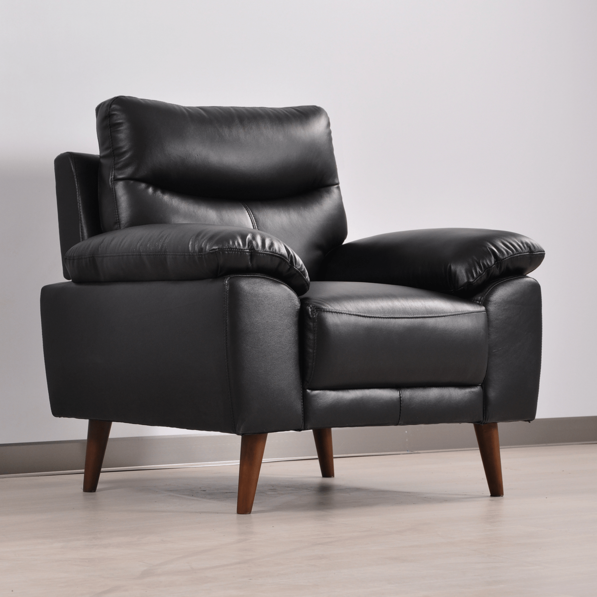 Vantage black armchair in a modern living room set, angled view with decor and soft ambient lighting.