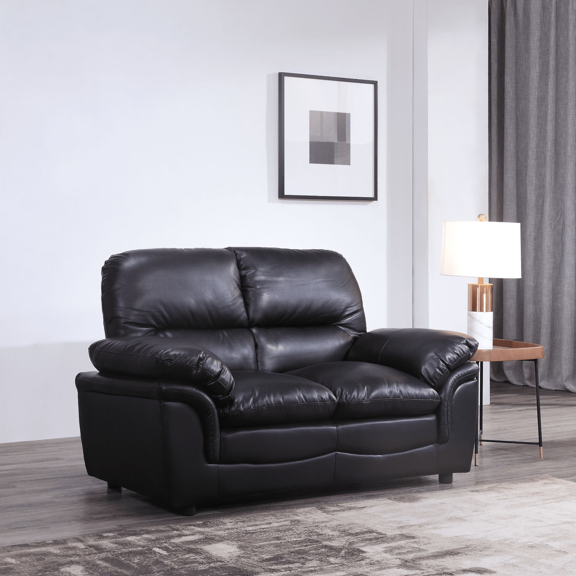 Black leather sofa in a living room setting with a lamp and wall art.