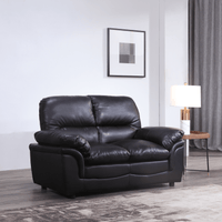 Black leather sofa in a living room setting with a lamp and wall art.