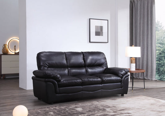 Black leather sofa in a living room setting with a lamp and framed picture on the wall.