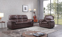 Brown leather sofa and chair set in a living room with large windows.