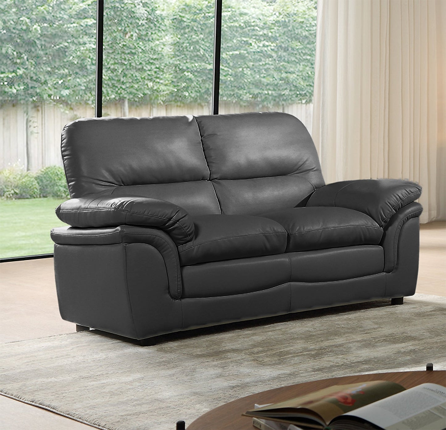 Gray leather sofa in a living room with large windows and a rug.