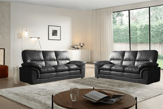 Modern living room with black leather sofas and a round wooden coffee table.