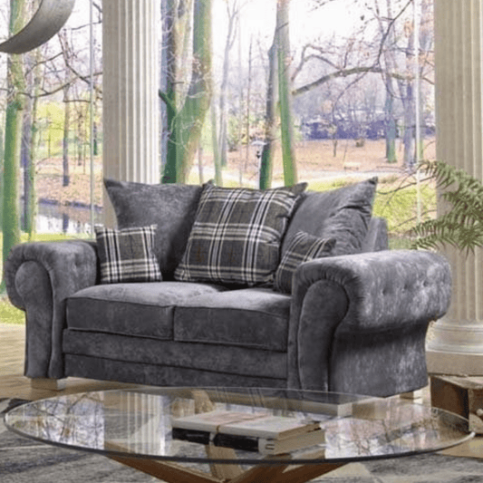 Gray sofa with plaid cushions in a room with large windows showing a garden view.